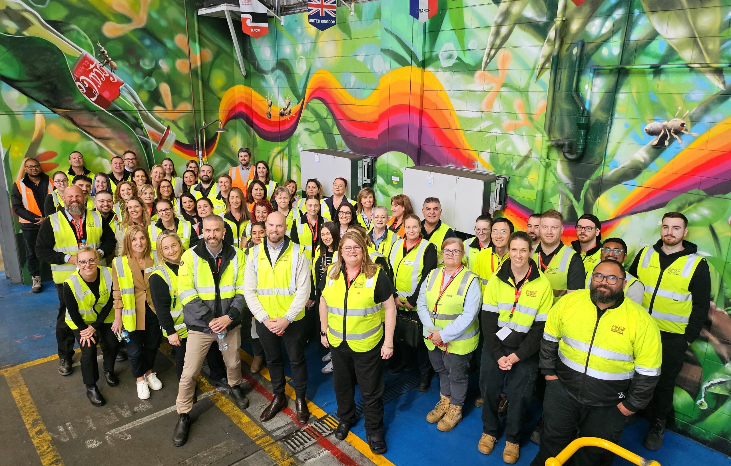Group of smiling people in front of a colourful wall